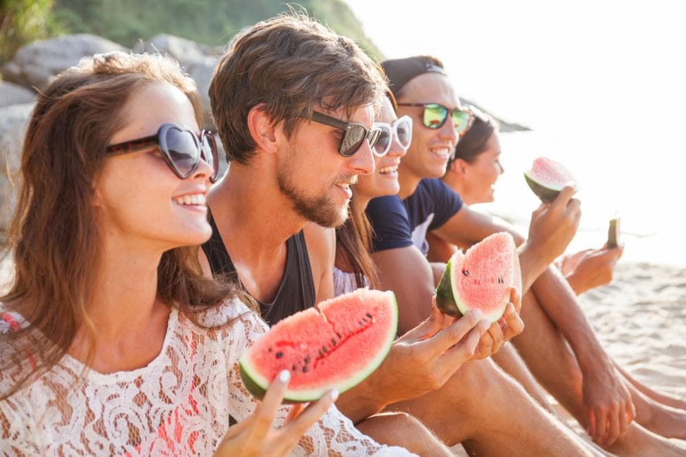friends eating watermelon on beach
