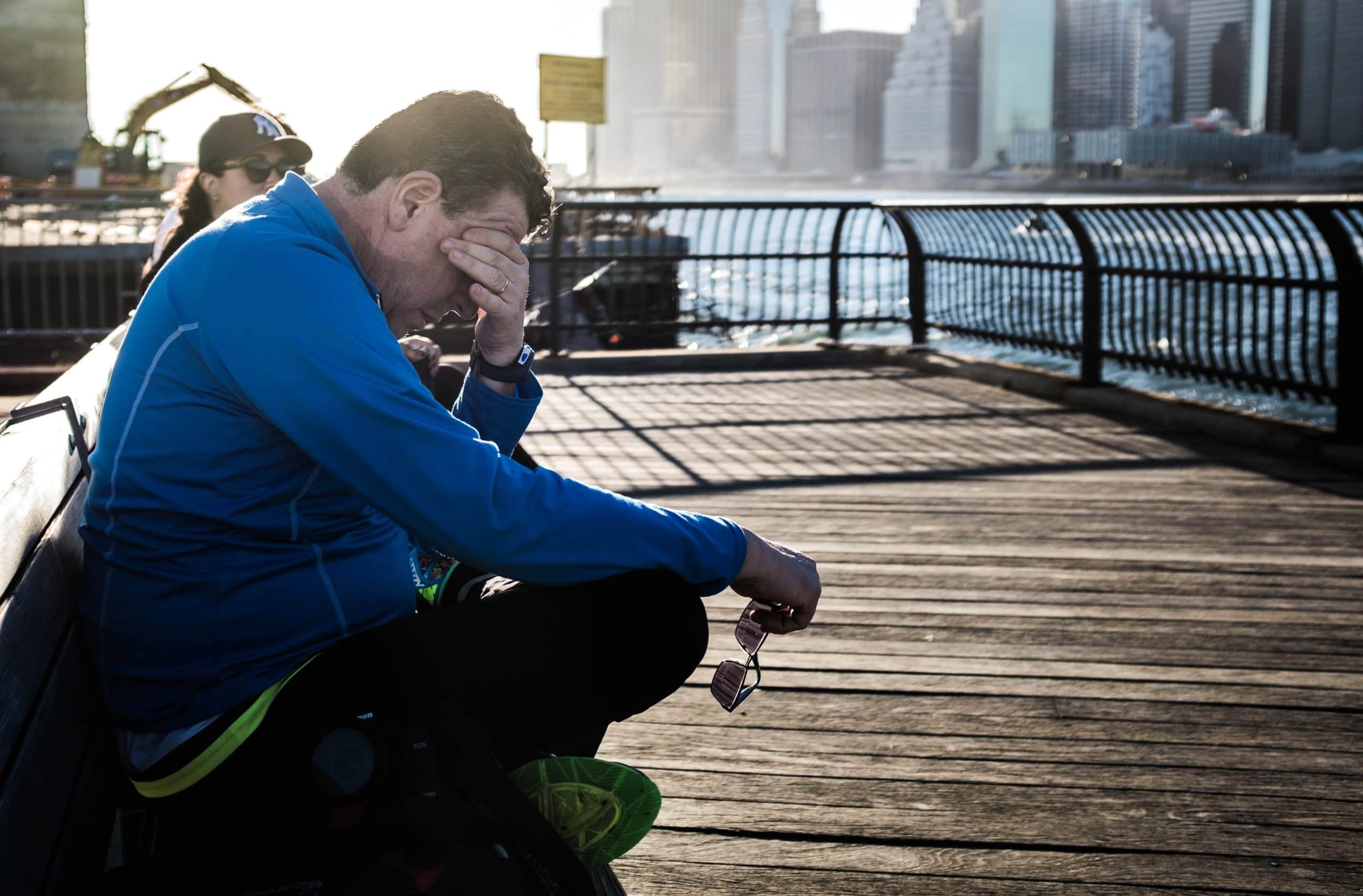man sitting on pier, hands on his face