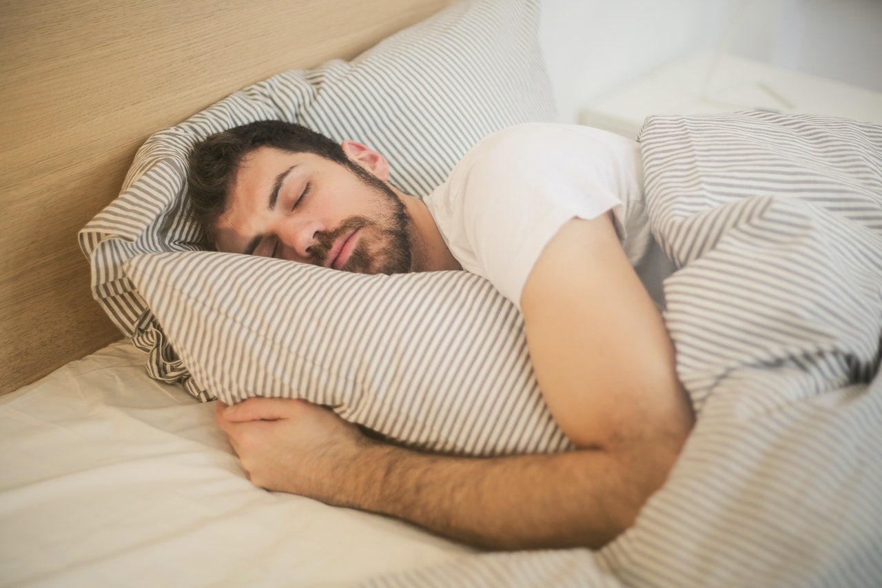 man in bed clutching pillow